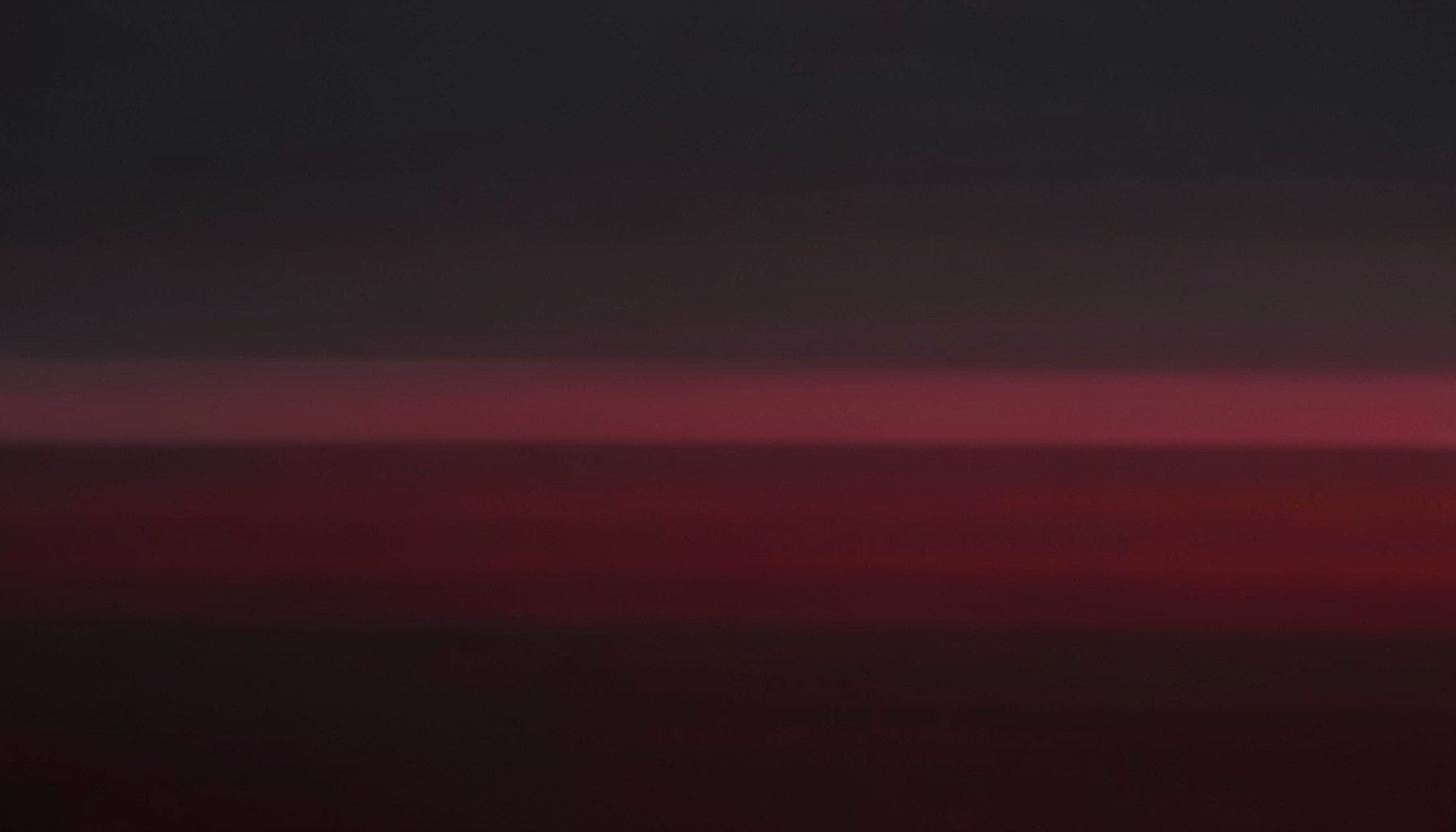 A duotone background image in deep charcoal and muted crimson, rendered as soft horizontal bands suggesting a wide, calm horizon.