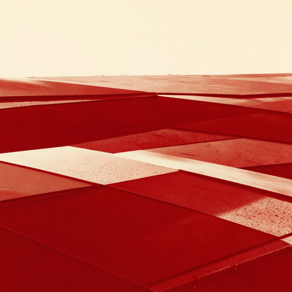A duotone photograph in warm brick red and soft cream, depicting a calm abstract field of layered geometric panels suggesting growth and structure.